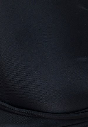 Nahaufnahme eines glatten schwarzen Stoffs mit subtiler diagonaler Struktur und einer gefalteten Naht nahe dem unteren Rand.