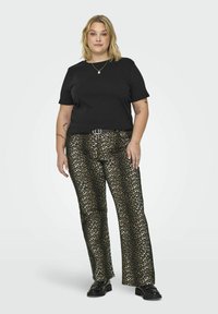 Camiseta preta de manga curta combinada com calças de estampa de leopardo em preto e dourado, apresentando um cinto com fivela arredondada. O modelo usa sapatos pretos.