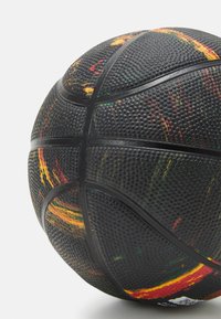 Black basketball featuring a textured surface with vibrant multicolored splashes (red, yellow, green) and standard rubber panels and seams.