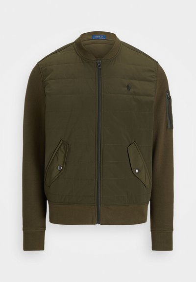 Casaco bomber verde oliva com frente acolchoada, fecho de correr completo, punhos em ribana e dois bolsos frontais. Possui um bolso com fecho de correr na manga.