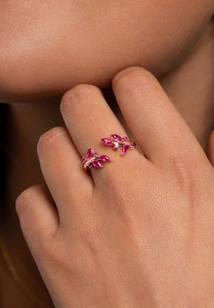 Anillo ajustable rosa con piedras preciosas rosa en corte marquise y pequeñas piedras transparentes, en un diseño de metal pulido curvado.