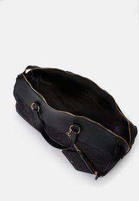 Sort duffel taske med en tekstureret mønster, guld lynlås, dobbelt håndtag og en forlomma med en lille lynlås. Rummeligt indre.