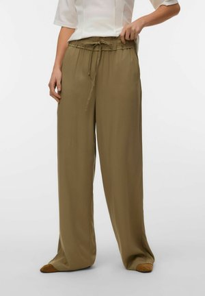 Løstsiddende olivengrønne bukser med snor i taljen, båret med tan-farvede sko, kombineret med en hvid top med trekvartlange ærmer.