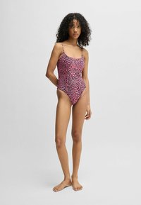 Eén stuk badpak in het roze met een zwart panterprint. Beschikt over dunne verstelbare bandjes en een hoge uitsnijding voor een aansluitende silhoët.