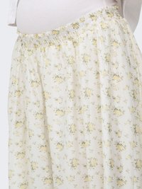 Gros plan d'une jupe blanche à petits motifs floraux jaunes avec une taille élastique portée sur un haut blanc côtelé.