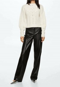 Pull en tricot crème avec un motif texturé en losanges, associé à un pantalon en cuir noir taille haute et des talons métalliques pointus.