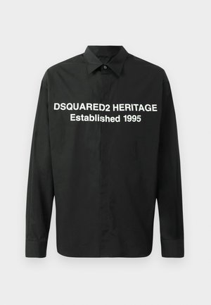 Chemise noire à manches longues en tissu lisse avec un texte blanc audacieux : « DSQUARED2 HERITAGE Établi en 1995 » sur le devant.