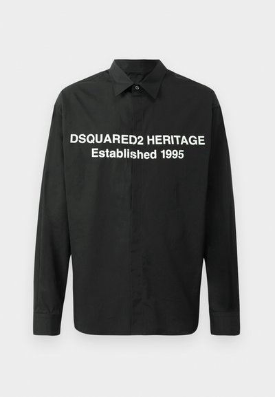 Must mustriga T-särk siledast kangast, millel on julge valge tekst: "DSQUARED2 HERITAGE Asutatud 1995" esiküljel.