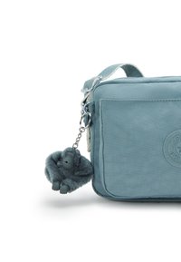 Borsa in tessuto morbido e blu con chiusura zip, caratterizzata da una forma arrotondata e un portachiavi peloso a forma di gorilla.