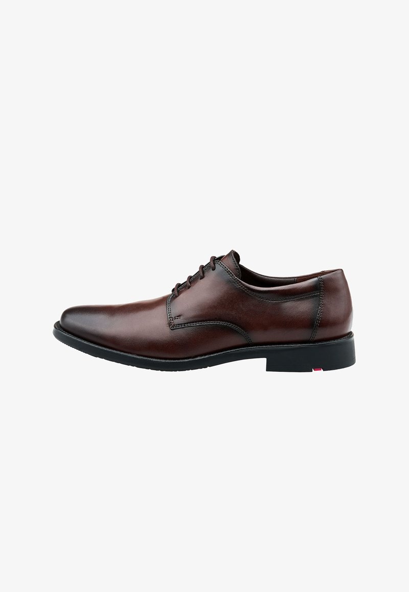 Zapato de vestir de cuero marrón con una textura suave, punta redondeada y cuatro ojetes para los cordones. Presenta una suela de goma negra y detalles de costura sutiles.