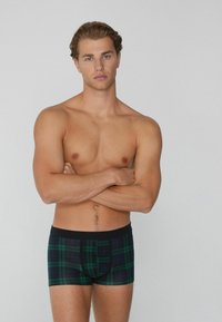 Boxershorts mit einem grün-blauen Karomuster und einem schwarzen elastischen Bund. Der Stoff wirkt weich und enganliegend.