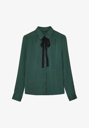 Blouse en soie verte avec un col classique, des manches longues et un nœud en ruban noir au cou. Comprend une fermeture à boutons à l'avant et des détails plissés.