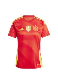 Červený sportovní dres se žlutými akcenty, zdobený logem Mistrovství světa žen FIFA a státním emblémem Španělska. Krátké rukávy, kulatý výstřih.
