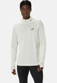 Langdurige sportshirt met lange mouwen in lichtbeige, met een hoge kraag, duimdoorsnedes en kleine ventilatiegaten op de schouders. Logo op de borst.