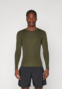 Dlouhý rukáv, olivově zelený sportovní top se slim fit střihem, vyrobený z lehkého materiálu, s malým černým logem na hrudi.