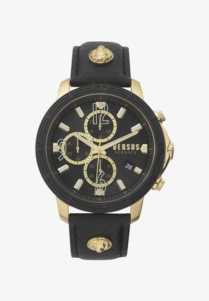Gold-tone chronograph watch with a black textured strap, featuring a black dial, white hour markers, and a distinct lion head accent on the strap.