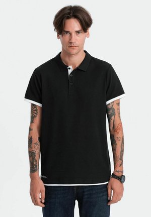 Camisa polo negra de tejido ligero, con tapeta de tres botones y acentos blancos en las mangas y el cuello, combinada con jeans azules.