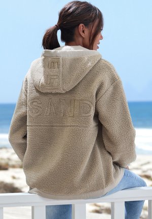 Fleece-Kapuzenjacke in Beige mit strukturiertem Oberflächenmaterial, besticktem "SAND" auf dem Rücken und kontrastierender, cremefarbener Innenfütterung.