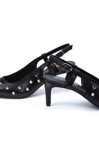 Tacones slingback de cuero negro con acentos de tachuelas plateadas, diseño de punta afilada y un delgado tacón de aguja. Correas texturizadas para mayor soporte.