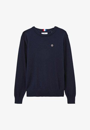 Pull marine bleu à manches longues, avec un ourlet et des poignets côtelés, un col rond et un petit logo circulaire sur la poitrine. Texture en tricot douce.