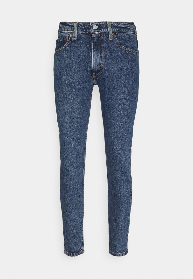 Jean skinny taille haute en denim bleu foncé avec bouton à l'avant, fermeture éclair, passants pour ceinture, ainsi que poches avant et arrière sur fond blanc.