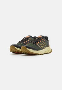 Green and black running shoes with orange accents, textured mesh upper, and cushioned sole featuring a rugged tread pattern.
