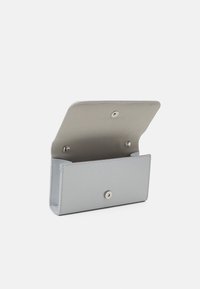 Portefeuille en cuir argenté à texture lisse, doté d'une fermeture à bouton-pression et d'un compartiment ouvert pour le rangement.