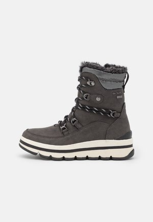 Ciemnoszary zimowy but z futrzanym wykończeniem, czarno-białymi paskowanymi sznurowadłami, grubą białą podeszwą z czarnym bieżnikiem oraz haczykami do sznurowania.