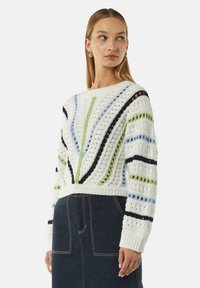Gebreide trui met een witte basis en diagonale strepen in groen, blauw en marineblauw, opengewerkte textuur en een cropped pasvorm.