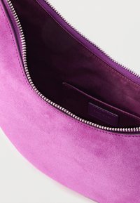 Liila mokkanahkalaukku, jossa on hopeinen vetoketju yläosassa, sileä pinta ja sisätasku, jossa on samansävyinen vuori.