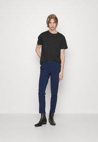 Černé tričko s krátkým rukávem, slim-fit námořnické kalhoty a černé kotníčkové boty. Jednoduchý design s hladkým povrchem a přiléhavým střihem.