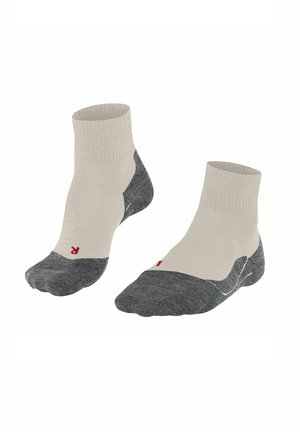 Chaussettes montantes en beige clair et gris foncé. Fabriquées en tissu avec des bord-côtes, des coutures renforcées et un petit logo rouge.