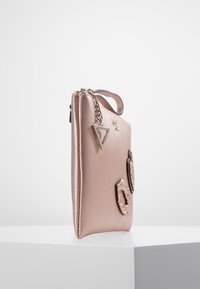 Rosa Clutch aus Kunstleder mit strukturierter Oberfläche. Verfügt über dreieckige und runde Hardware-Akzente, Kettendetail und einen seitlichen Griff.