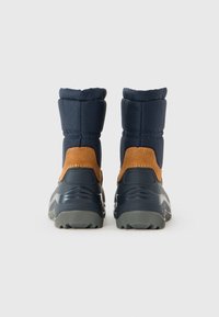 Une paire de bottes d'hiver bleu marine et marron avec un haut rembourré épais et des semelles en caoutchouc gris robuste, vues de l'arrière sur un fond blanc.