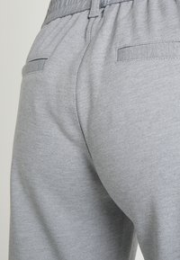 Graue Jogginghosen aus weicher Stoffqualität, mit einem gerippten Bund, zwei Gesäßtaschen und einer glatten Textur.