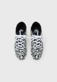 Et par sneakers med sort og hvid pixelmønster, udstyret med hvide snørebånd og sort indre foring, set ovenfra på en hvid baggrund.