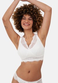 White lace bralette with a soft, textured finish, featuring a v-shaped neckline, floral lace accents, and a wide lace band.
