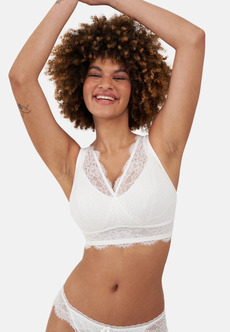 White lace bralette with a soft, textured finish, featuring a v-shaped neckline, floral lace accents, and a wide lace band.