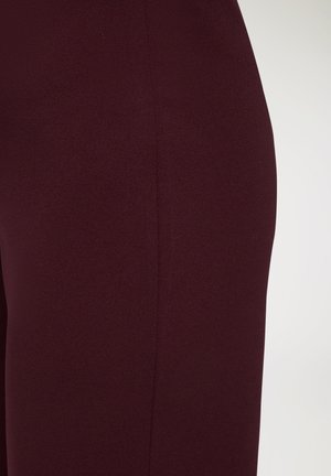Leggings bordeaux in morbido tessuto elasticizzato; texture liscia con una vestibilità aderente e dettagli discreti sulle cuciture laterali. Nessun hardware o pattern visibili.