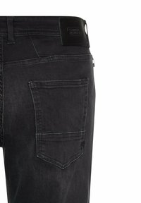 Zwarte denim jeans hebben een gladde textuur, een rechte pasvorm, een achterzak met subtiele stikseldetails en een zwart label op de tailleband.