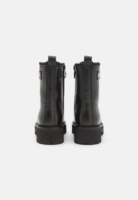 Bottines en cuir noir avec une finition texturée, bout rond, fermetures éclairs sur les côtés et semelle robuste. Présente un petit patch logo sur les côtés extérieurs.