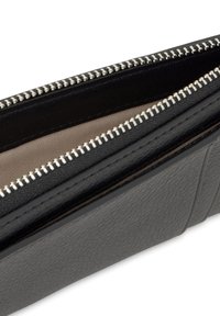 Czarny portfel ze skóry o gładkiej fakturze i srebrnym zamkiem błyskawicznym. Wnętrze wyścielone beżową podszewką. Zawiera wiele przegródek i szczegóły ze szwem.