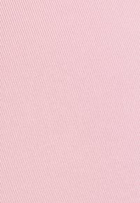 Nærbillede af lyserødt stof med en fin diagonalt vævet tekstur og små jævnt fordelte kvadratiske mønstre.