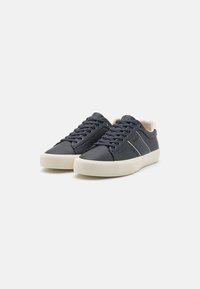 Tumedad sinised sneakers, mis on valmistatud tekstuuritud nahast ja millel on kreemcolorist kummitald. Omavad nöörimise disaini ja kontrastset külgpaneeli.