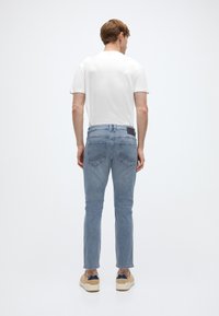 Ανοιχτό μπλε τζιν από denim με ίσια γραμμή, που διαθέτει μαύρη δερμάτινη ετικέτα στη πίσω ζώνη και δύο πίσω τσέπες.