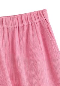 Rosa krinklat tyg med en hoprullad elastisk midja och strukturerad yta. Mjukt, lätt material.