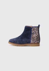 Navy Wildleder Stiefelette mit einem glitzernden, mehrfarbigen Einsatz an der Ferse, flacher brauner Gummisohle und einer Schlaufe für einfaches Anziehen.