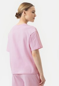 T-shirt en coton rose clair à manches courtes et à coupe décontractée, avec un col rond et une texture lisse, vue de dos.