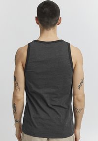 Débardeur gris sans manches avec des bordures noires, fabriqué en tissu léger, présentant une texture lisse et sans motifs visibles.