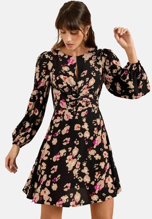 Schwarzblumenkleid mit Puffärmeln, Schlüssel-Ausschnitt und taillierter Taille. Es hat ein farbenfrohes Blumenmuster in Rosa- und Beigetönen.
